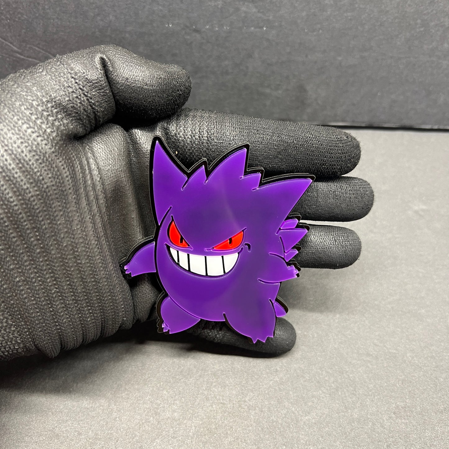 Purple Gengar inspired car emblem with red eyes and white teeth