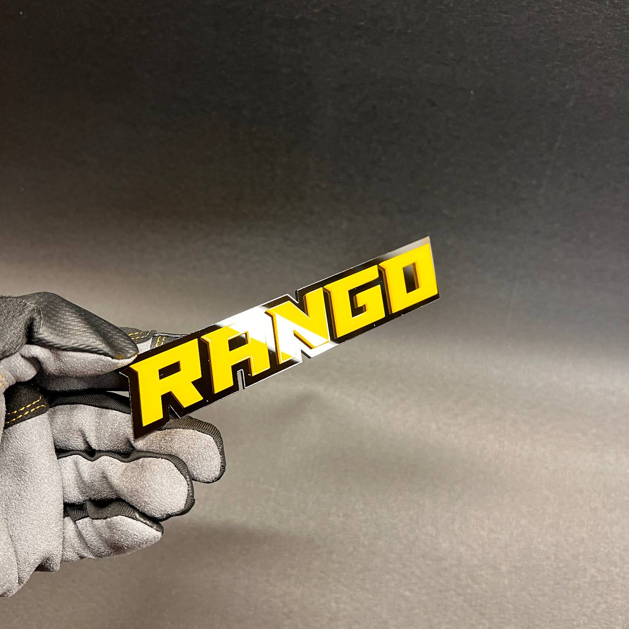 Custom Rango vehicle badge made with yellow acrylic and black background.
