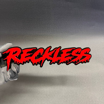 Reckless aggressive street racing style emblem with red lettering and black outline for Jeep Wrangler Gladiator custom exterior.