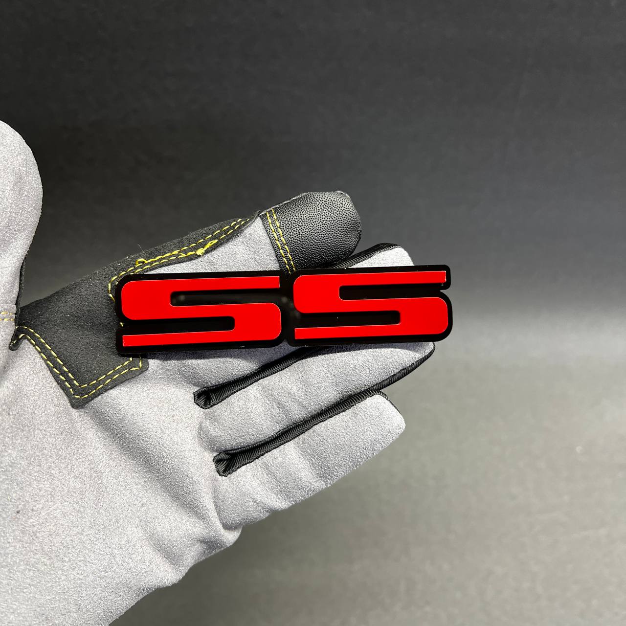 Red SS fender emblem shown in hand, made for Chevy Super Sport inspired custom styling.
