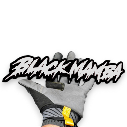 Black Mamba custom text badge shown in hand with red letters and black outline for vehicle exterior.