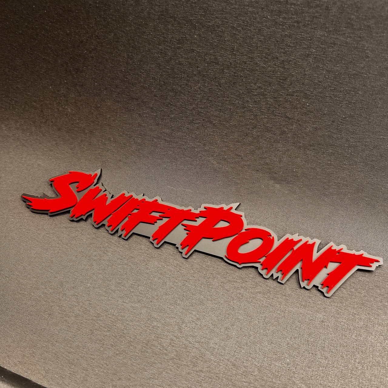 Swift Point automotive fender badge with red raised lettering on black backing