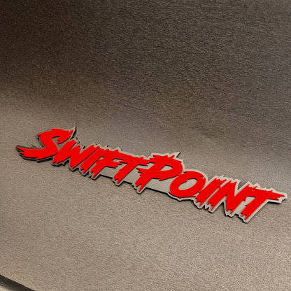 Swift Point automotive fender badge with red raised lettering on black backing