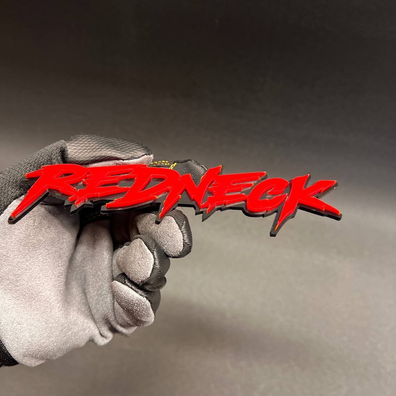 Glossy red Redneck automotive emblem for custom car exterior styling.