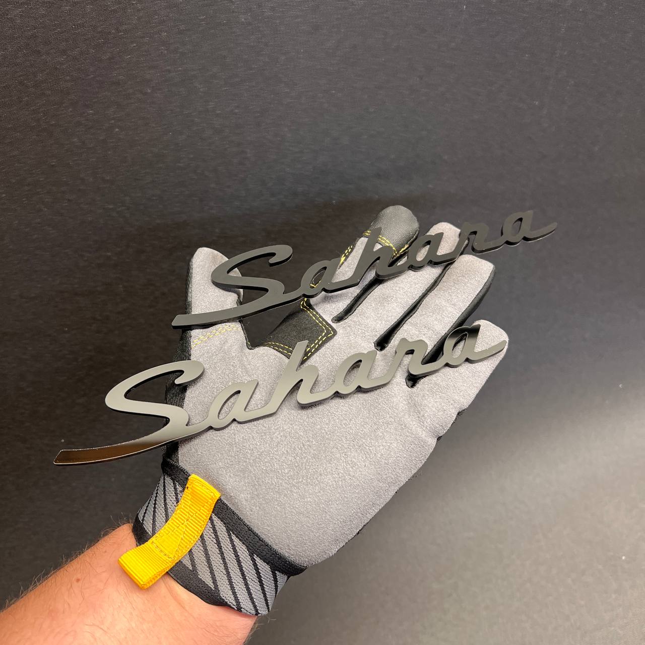 Black Sahara exterior car badge with smooth script lettering and 3M adhesive backing