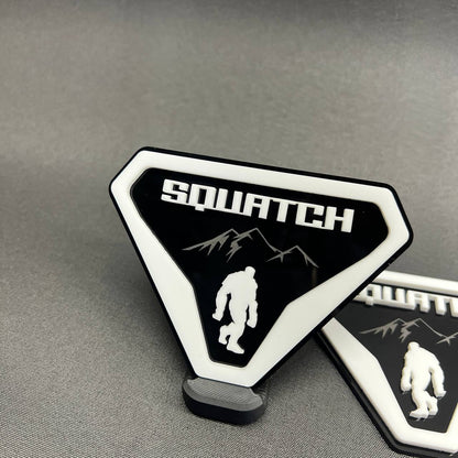 Sasquatch Bigfoot car badge in white on black with mountain artwork