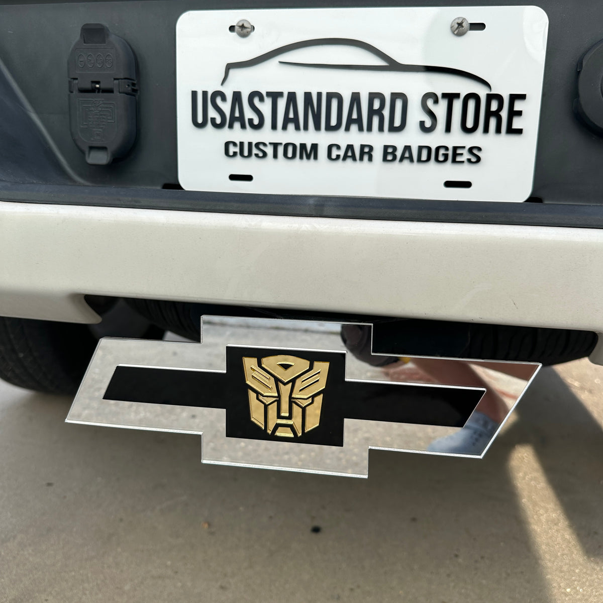 Chevrolet receiver hitch cover with silver Bowtie shape and gold Autobot center