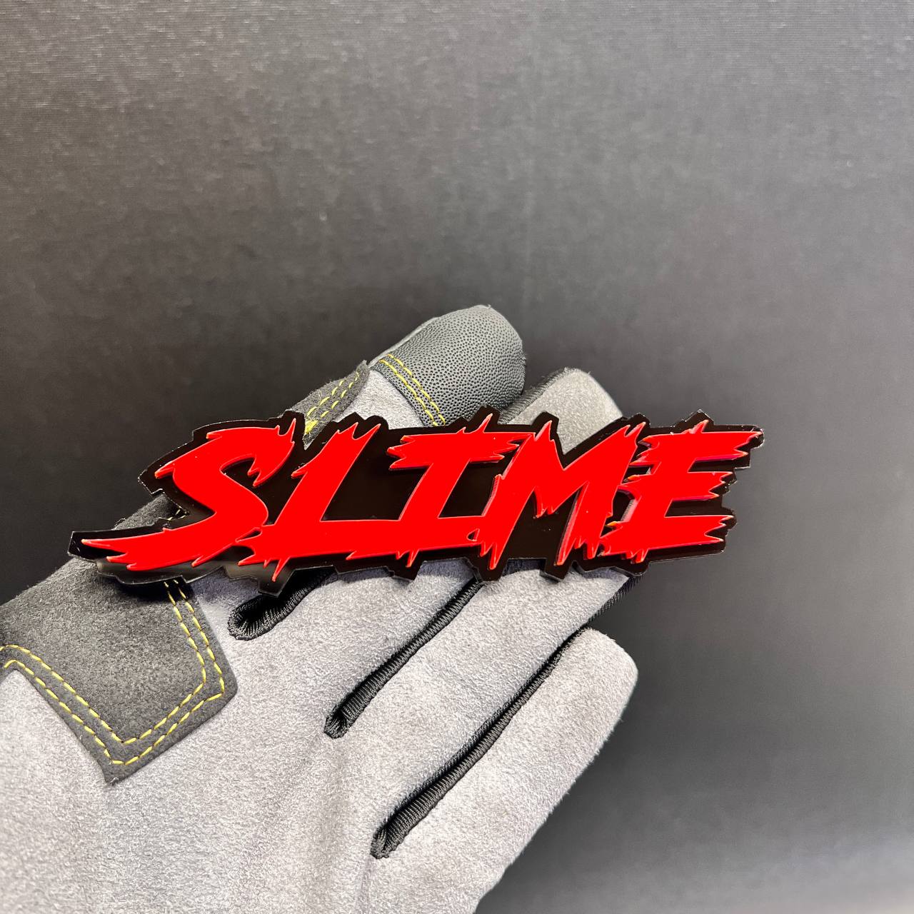 Red SLIME car badge fender emblem with a glossy black background