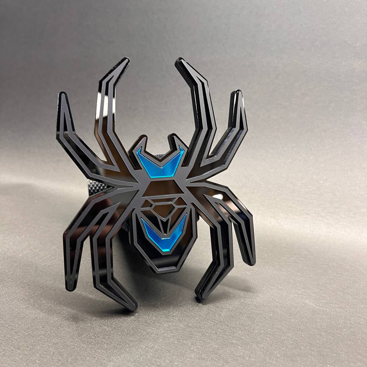 Exterior Black Widow car badge hitch cover with glossy black and blue detail