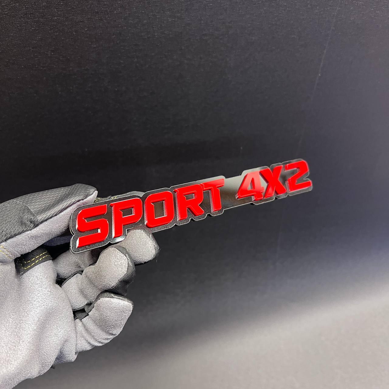 SPORT 4x2 text car badge with layered red lettering and black base.