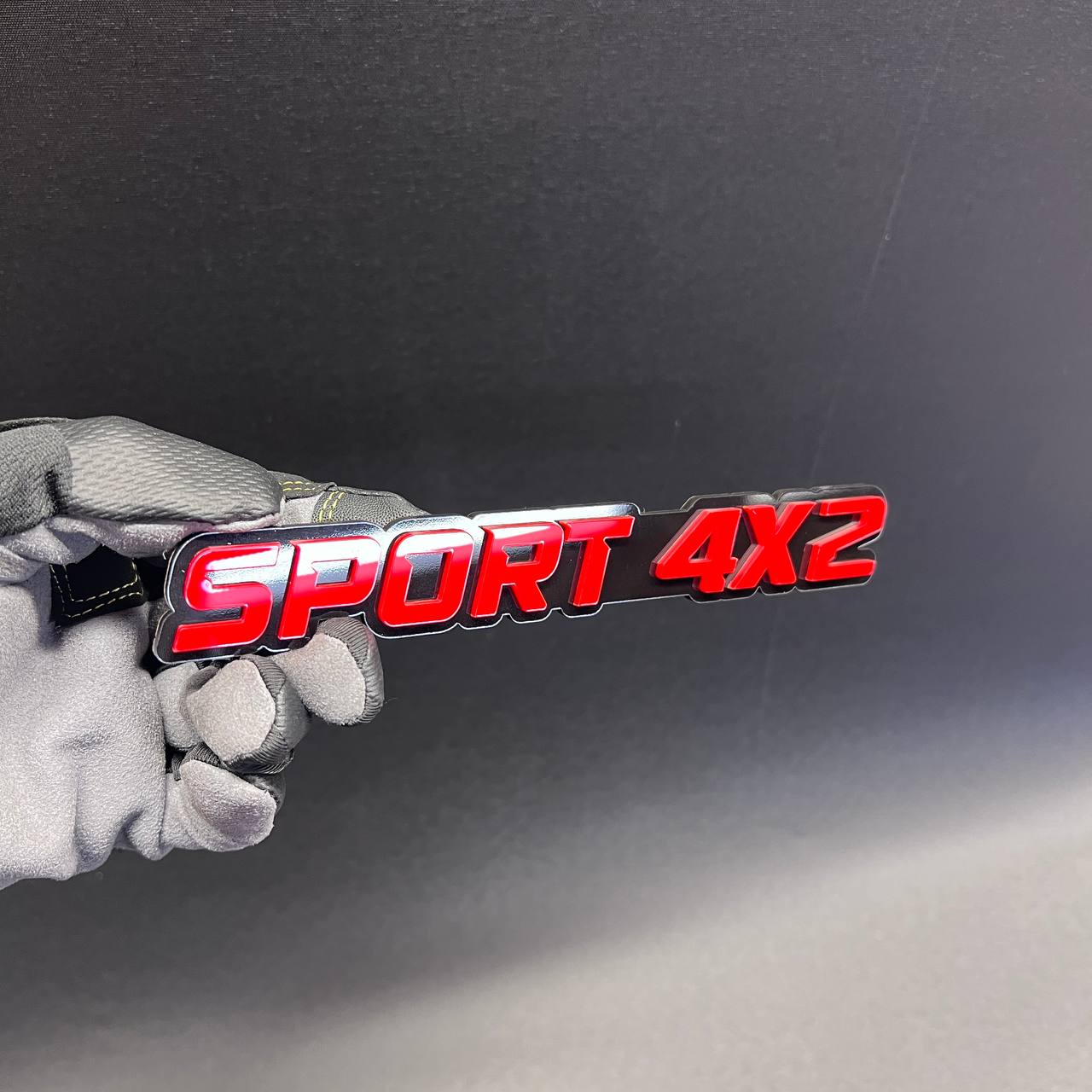 Red SPORT 4x2 car emblem badge for custom vehicle exterior styling.