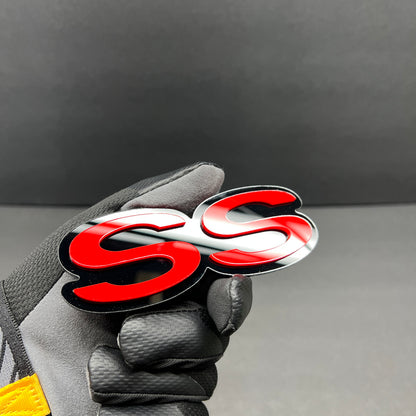 Close-up of SS text car badge in red with gloss black border.