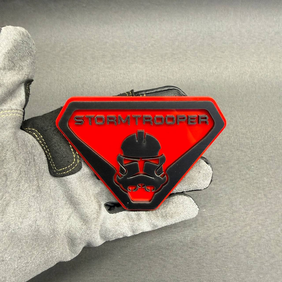 Custom Stormtrooper car badge featuring a black helmet design, raised lettering and bright red background for automotive exterior decoration.