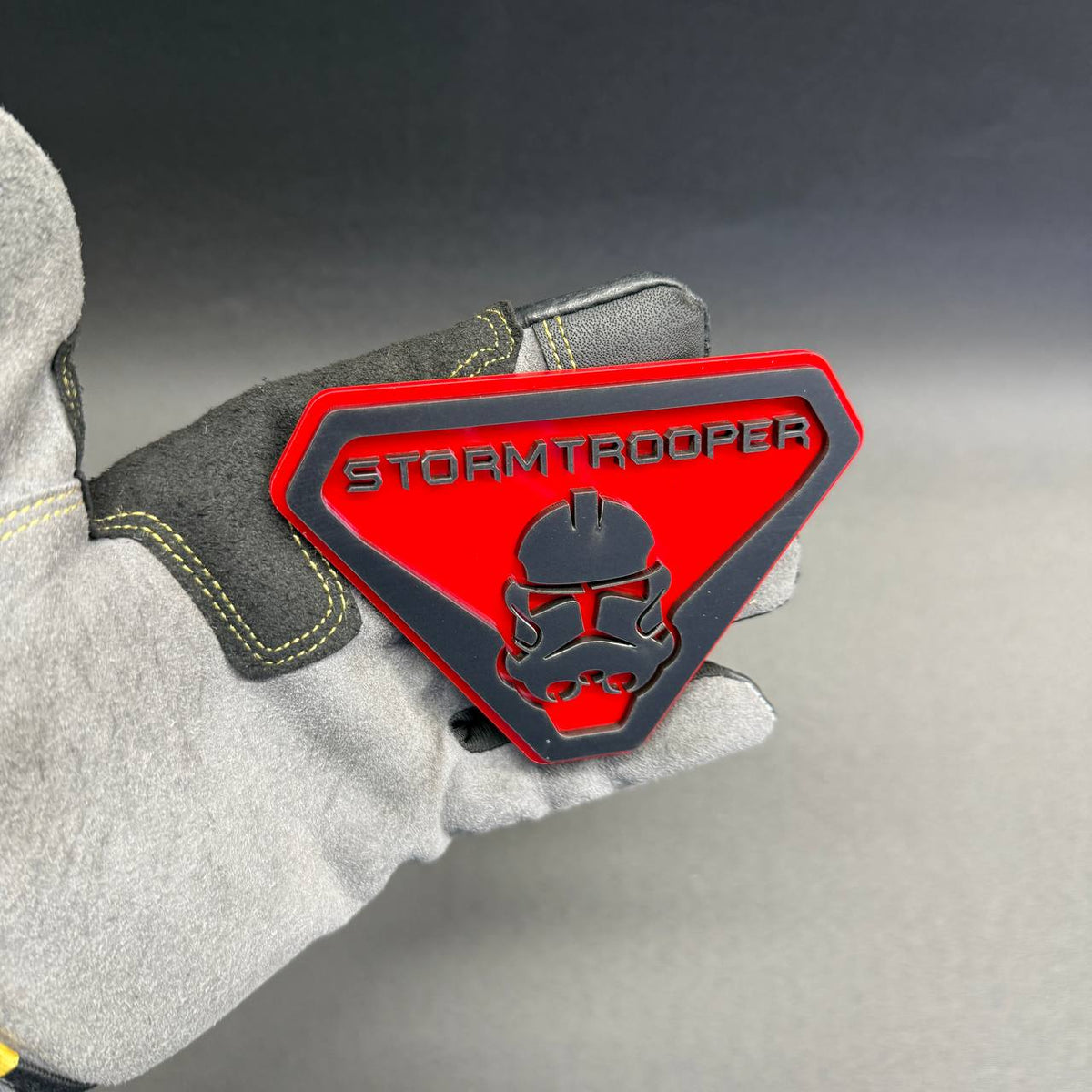 Stormtrooper themed automotive badge featuring a detailed black helmet on a red shield, suitable for Chevrolet Silverado, GMC Sierra and Tahoe.