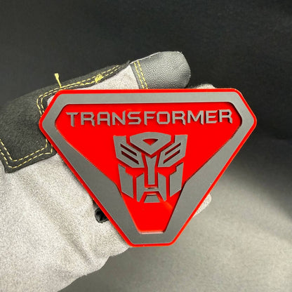 Transformer Autobot Badlands car badge featuring a red shield design with silver Autobot robot logo and Transformers lettering.