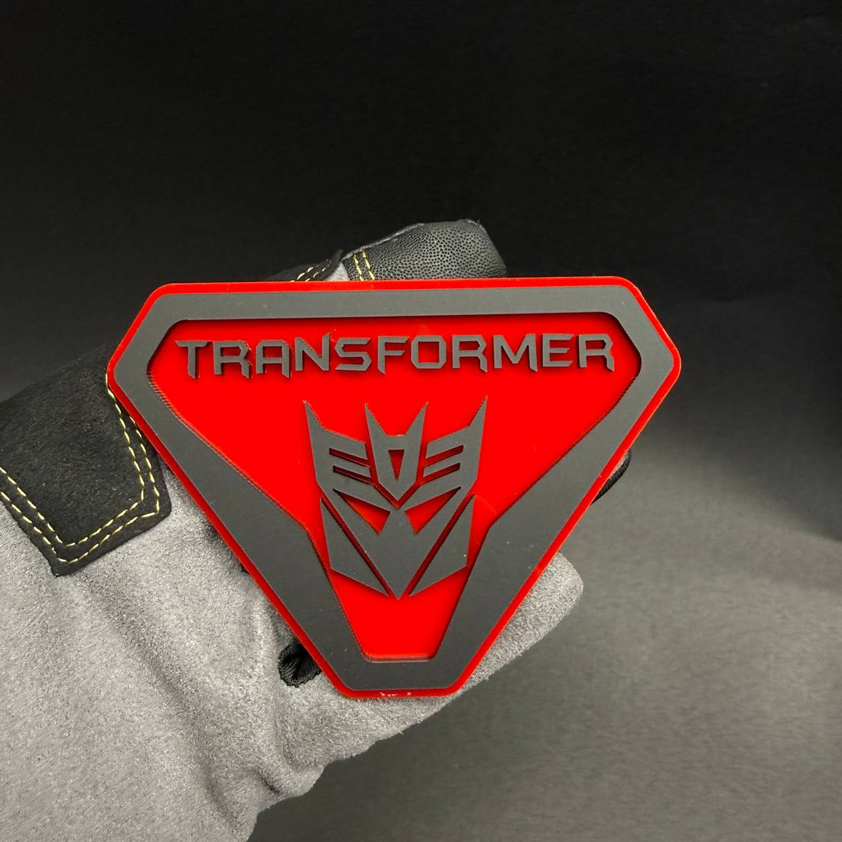 Transformer Decepticon Badlands car badge featuring a red shield design with silver Decepticon robot logo and TRANSFORMER lettering