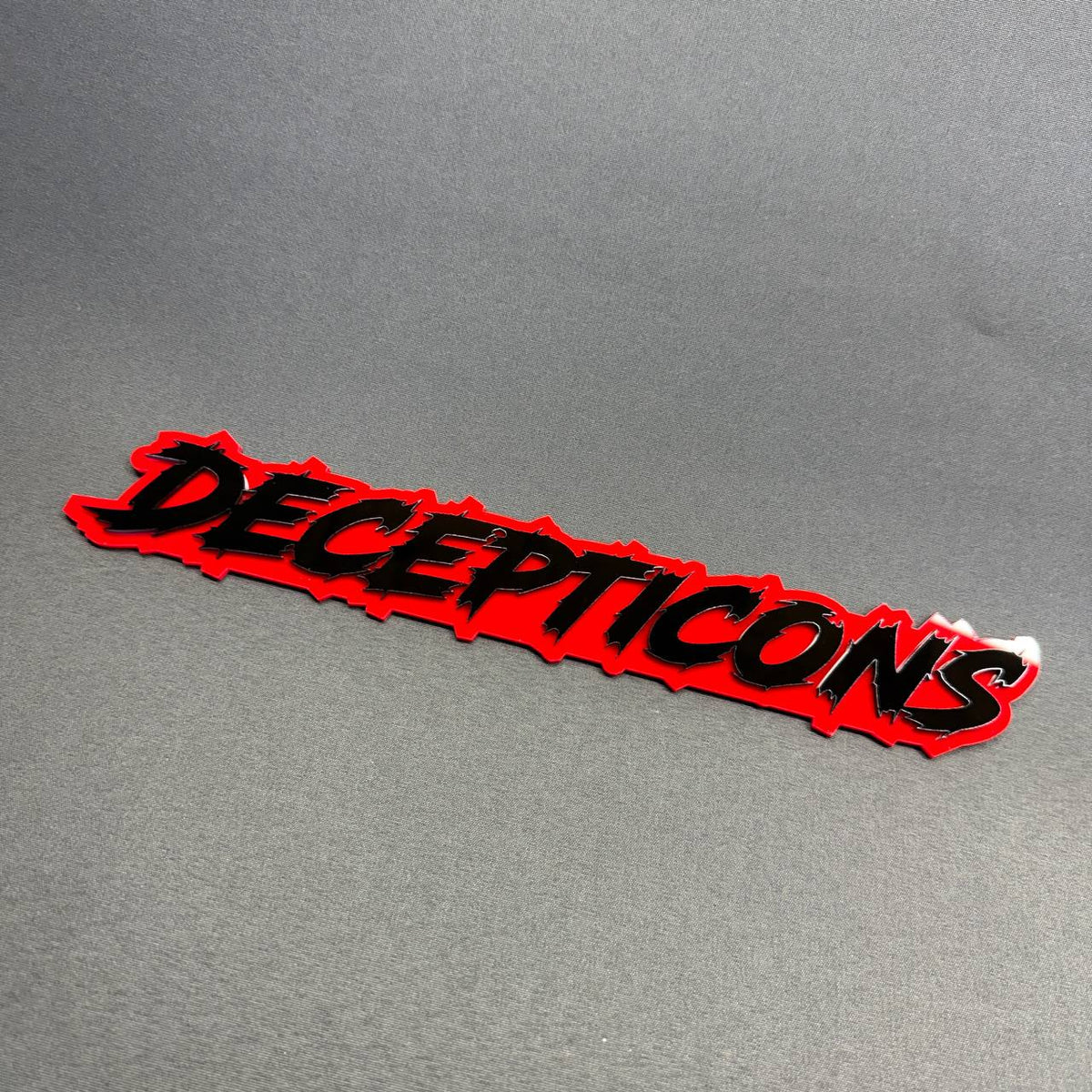 Transformers Decepticons custom truck emblem featuring laser-cut black lettering with a red acrylic backing, Chevrolet Silverado exterior decoration.