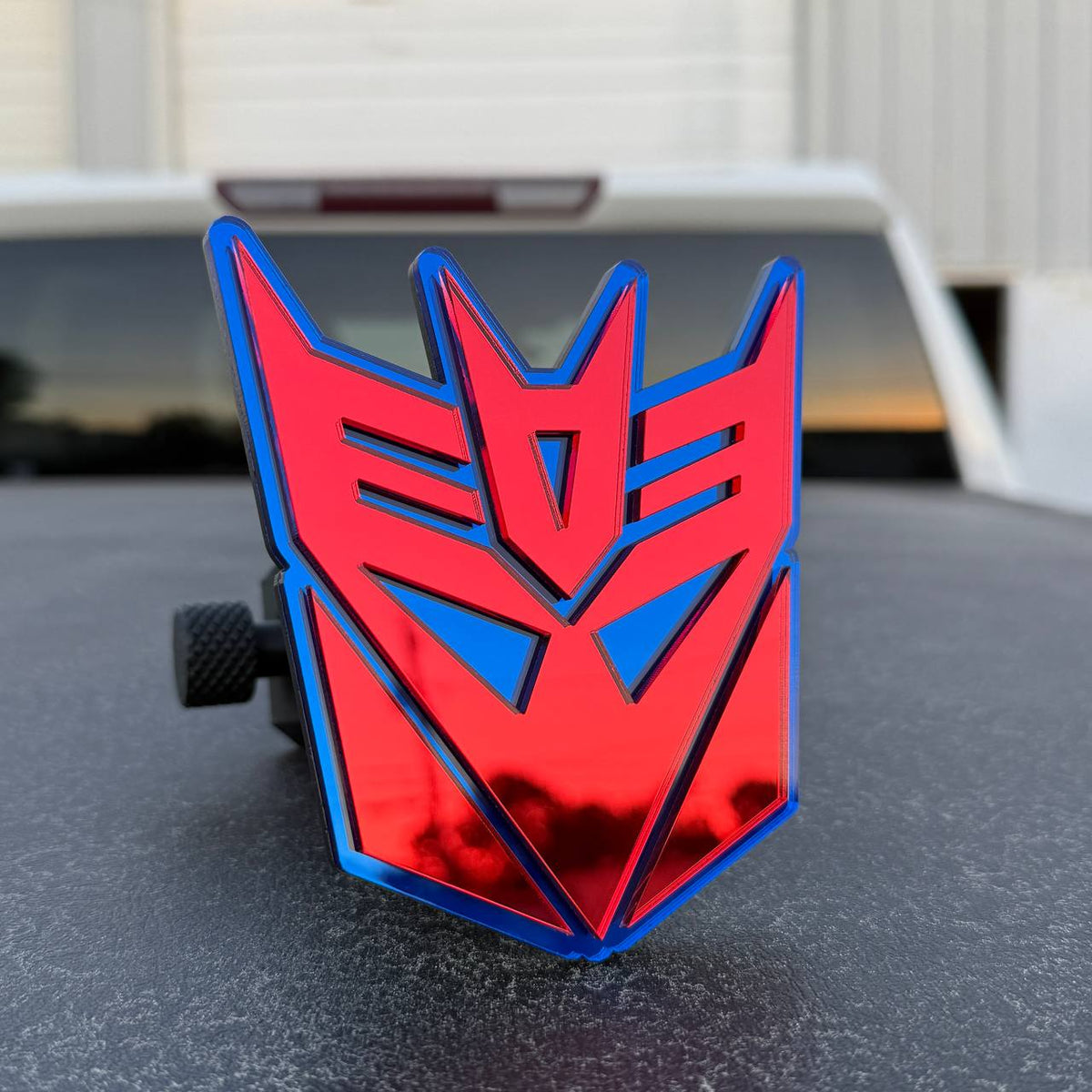 Reflective red and blue Transformers themed hitch cover for Toyota Tacoma pickup truck.