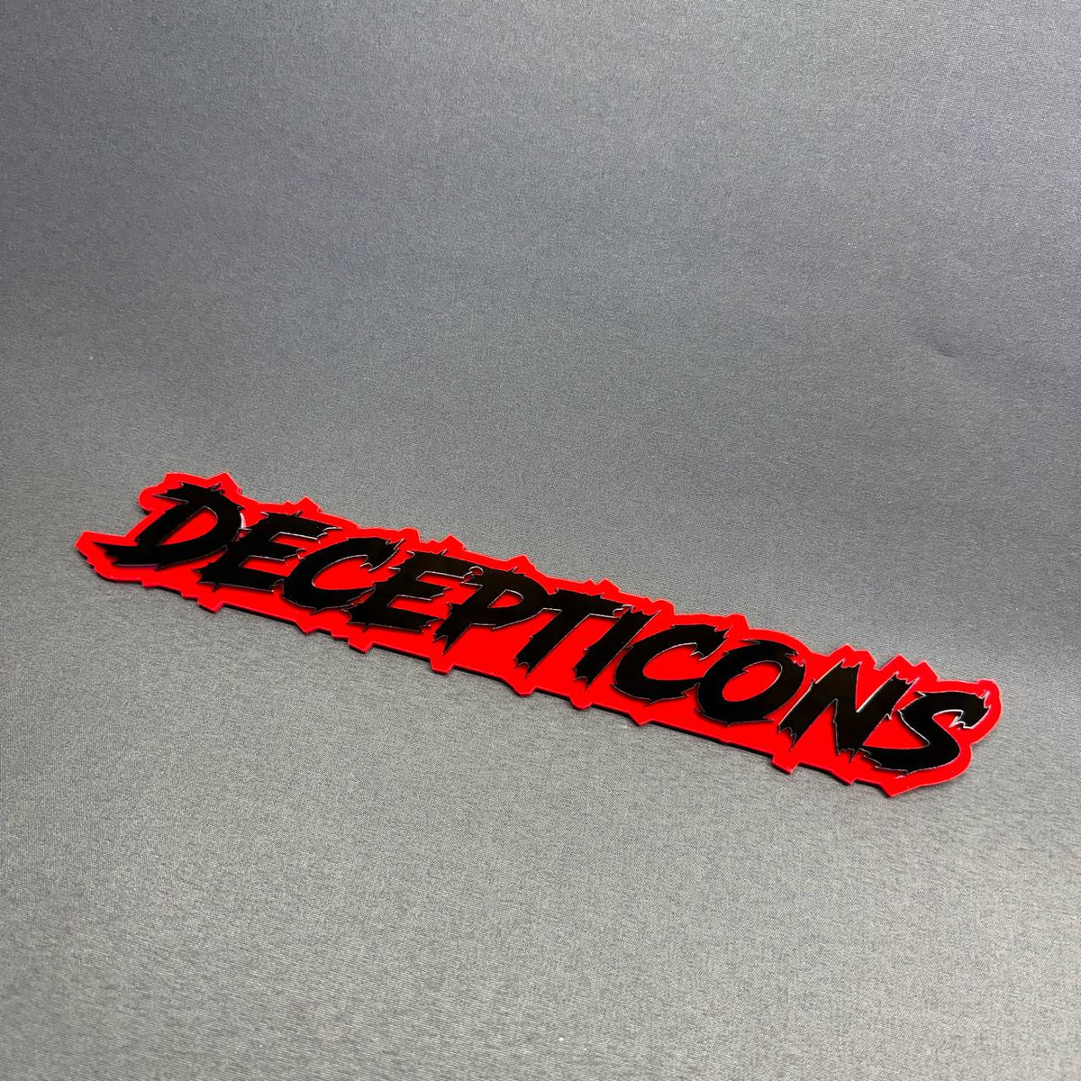 Decepticons 3D-look fender emblem with bold black aggressive lettering and bright red backing, Dodge Challenger custom exterior accessory.