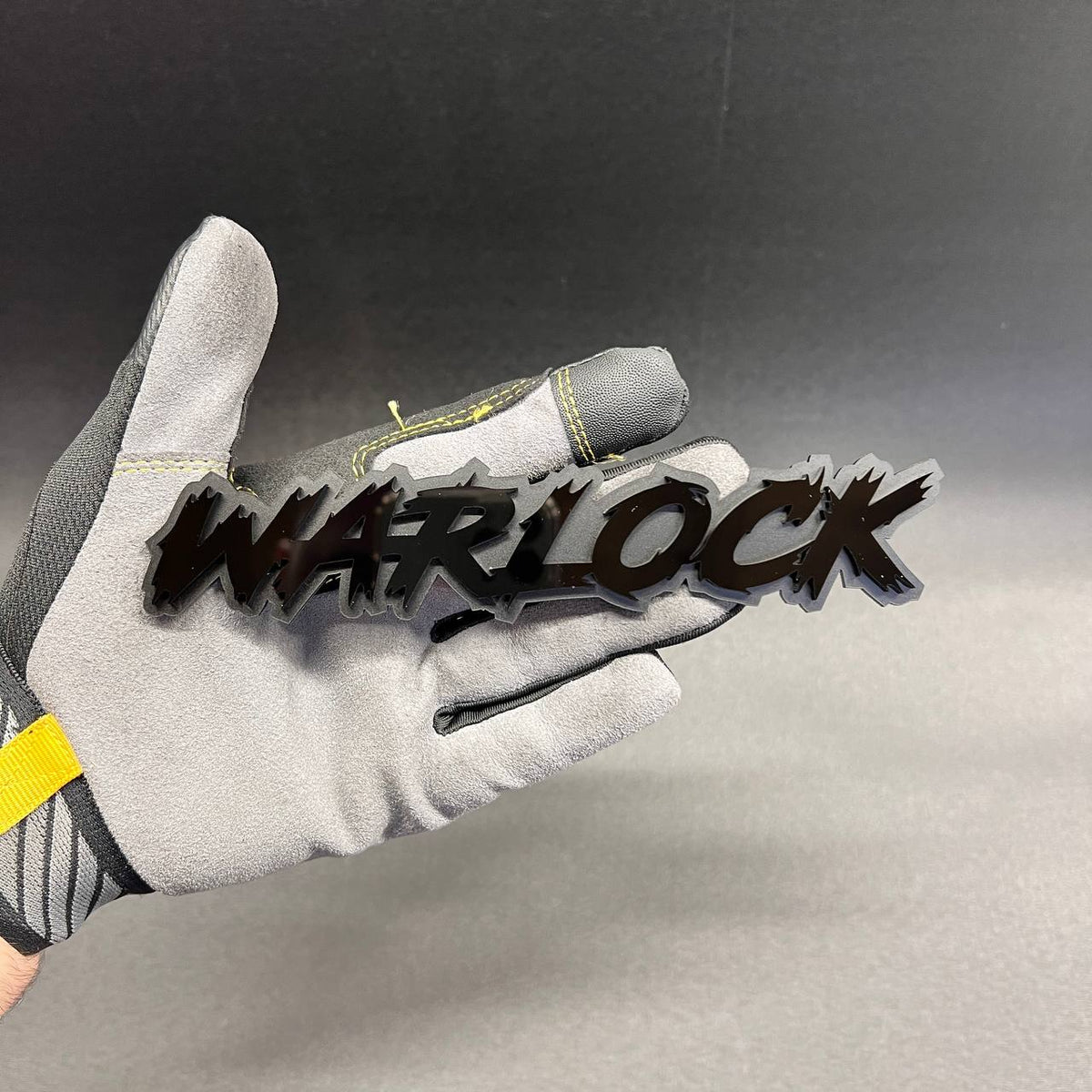 WARLOCK automotive text emblem with aggressive lettering and layered finish