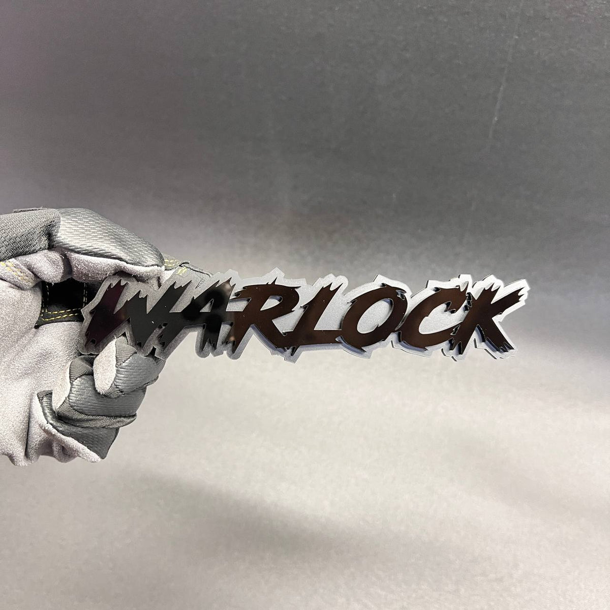 Black WARLOCK text badge with silver outline for automotive exterior decoration