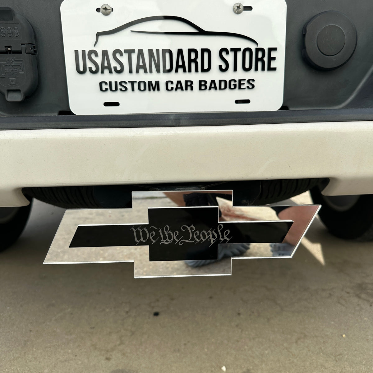 Silver and black Chevy Bowtie We the People hitch cover for truck exterior