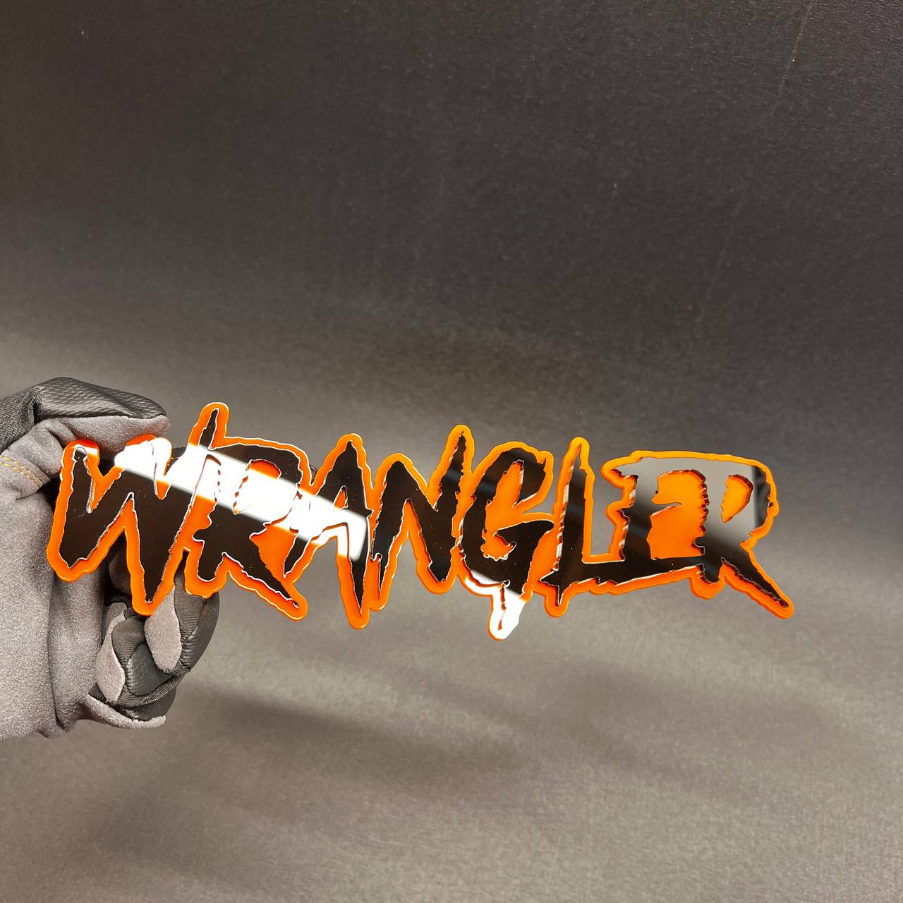 Personalized Wrangler car badge with bold black lettering and orange border.